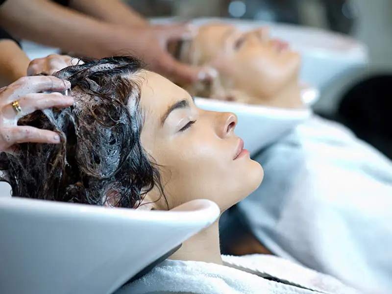 Patrons have their hair washed in basins by professional cosmetologists.
