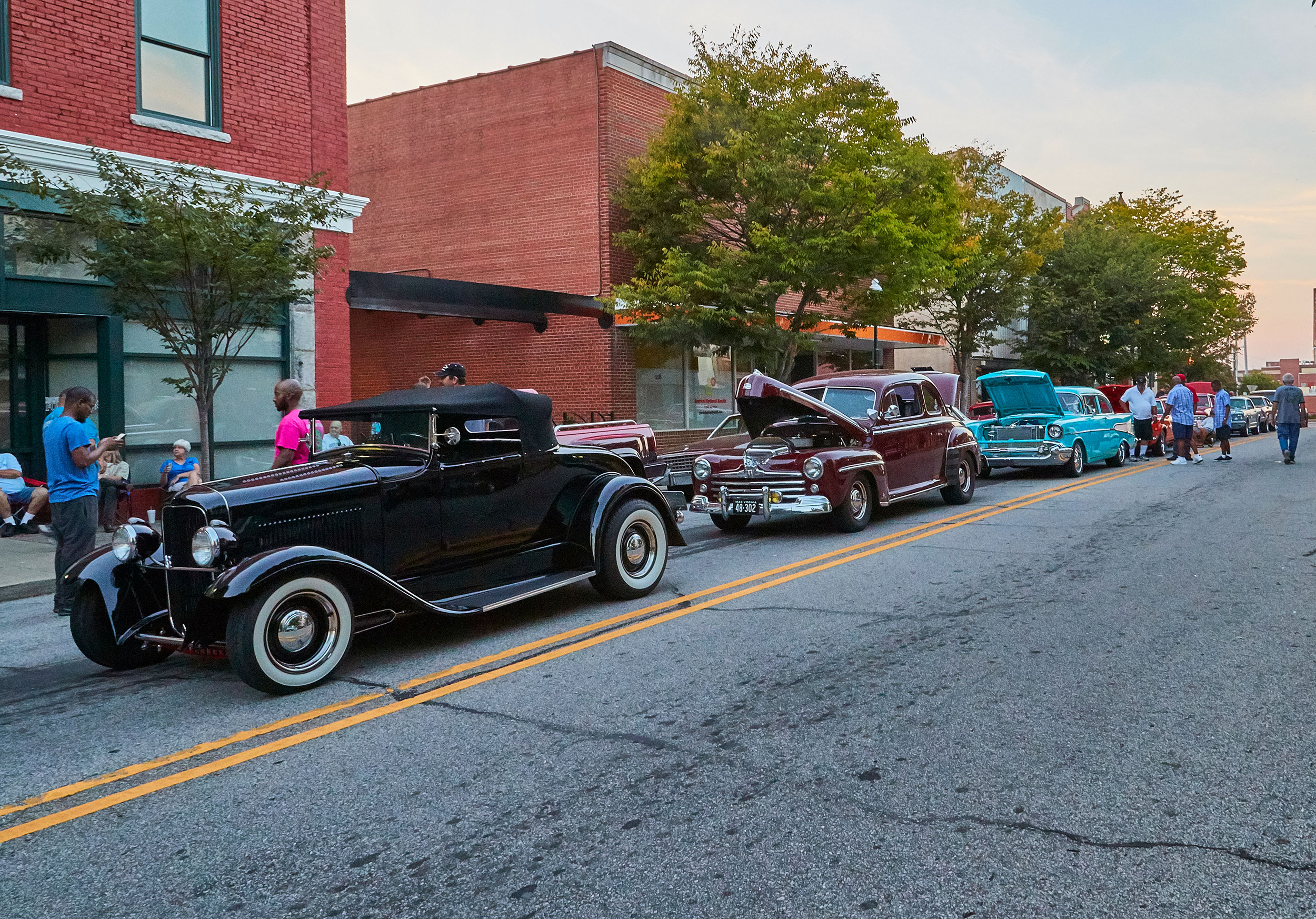 A line of classic vehicle on display at a street car show.