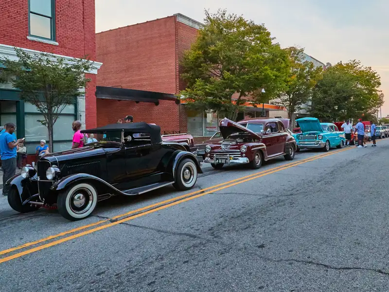 A line of classic vehicle on display at a street car show.
