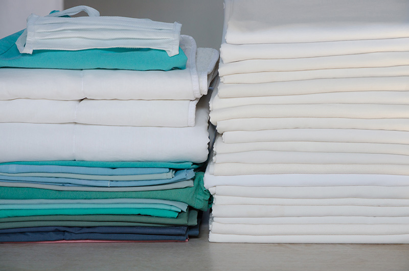 Towels of white, green and blue neatly stacked on a closet shelf.