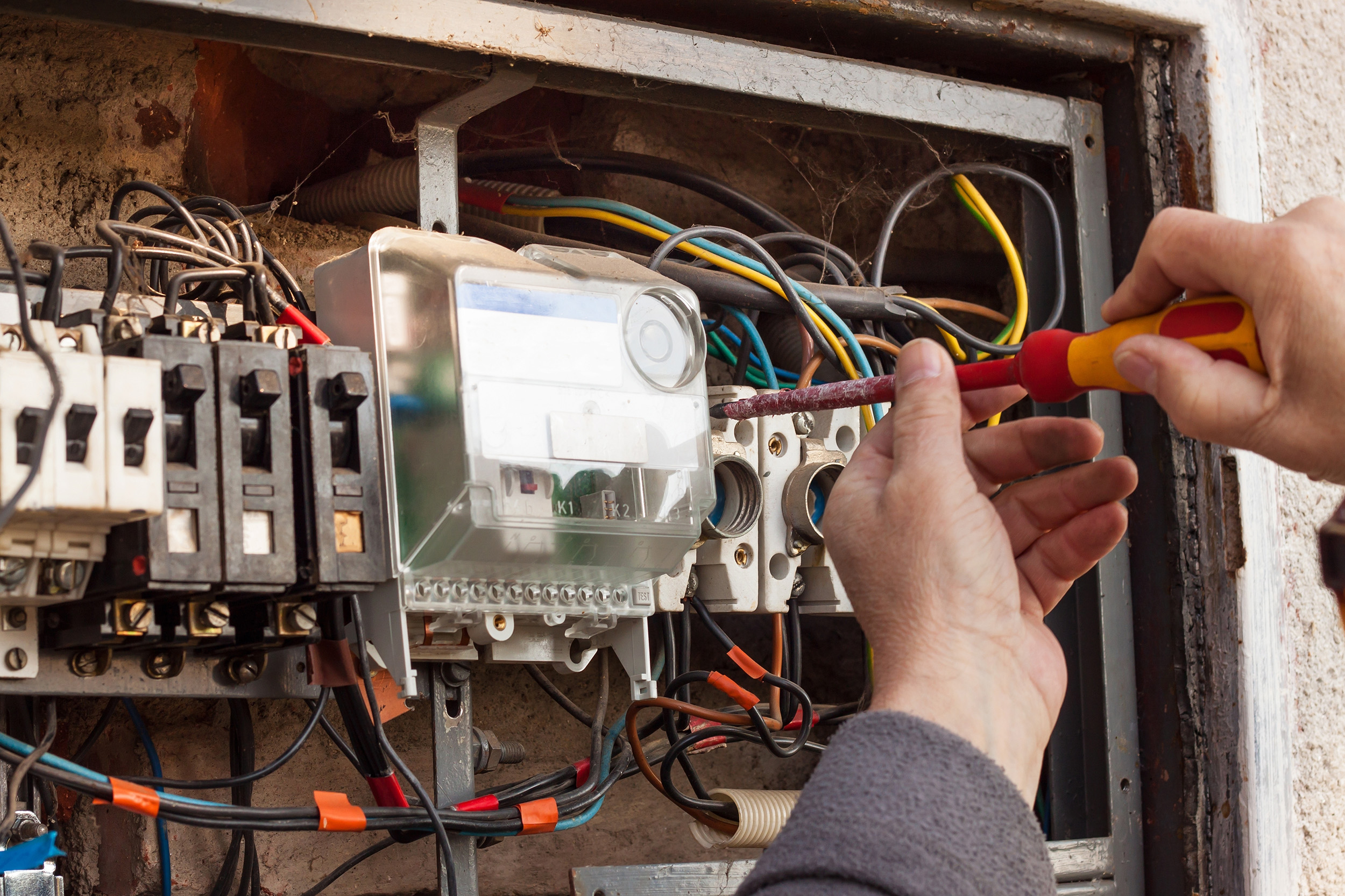 A electrician installs equipment in a breaker box.