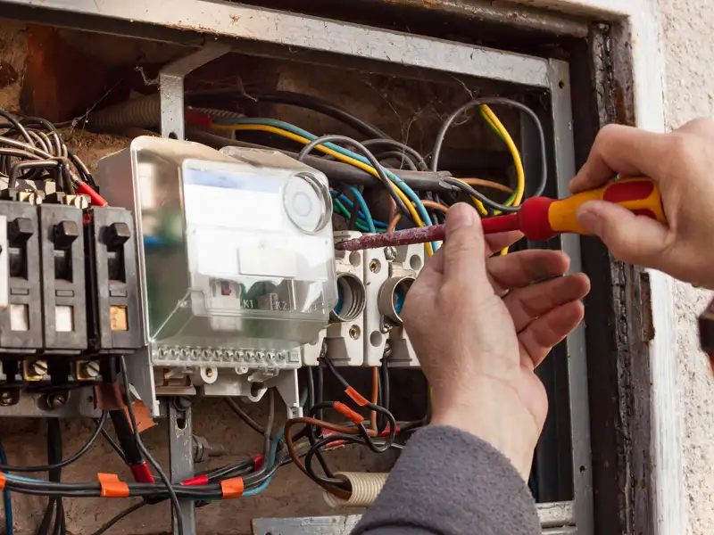A electrician installs equipment in a breaker box.
