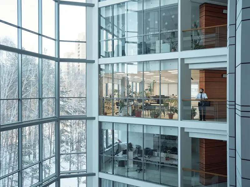 A person looks out from the balcony of a large office building.