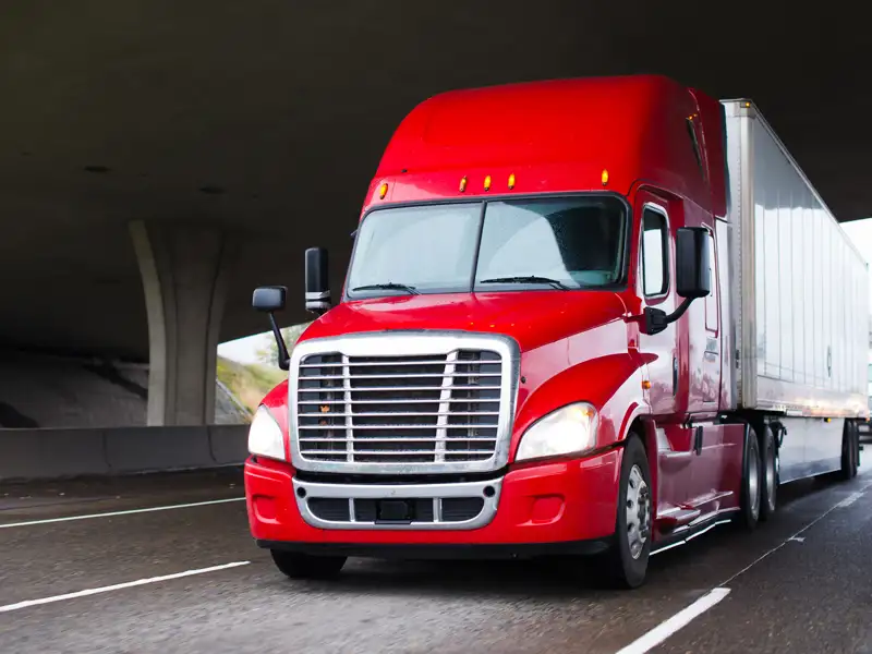 A red lorry drives through a highway overpass.