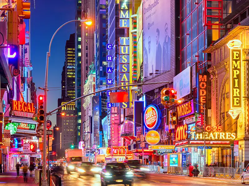 Bright neon dominates the street-level facades of a theatre district.