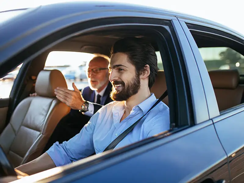 A rideshare driver takes direction from his backseat passenger.