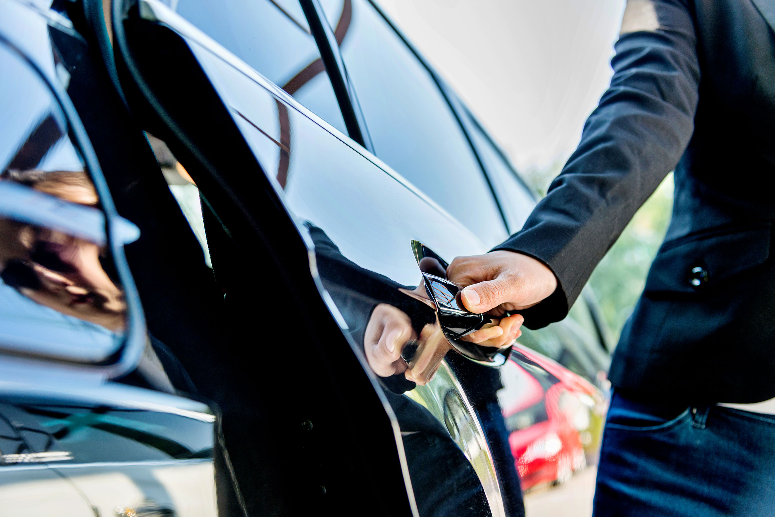 A chauffeur opens the door of a private car.