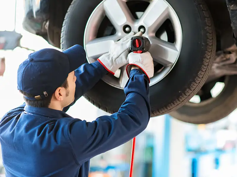 A technician installs new tires on a passenger automobile.