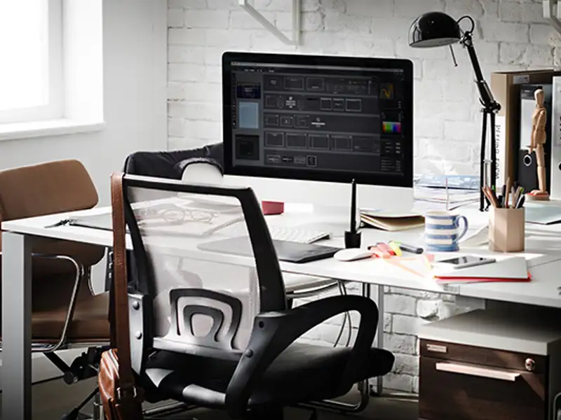 A workstation desk with a computer, lamp and other office items.