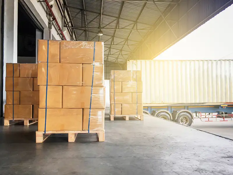 Stacks of cardboard boxes strapped to palettes on a loading dock.