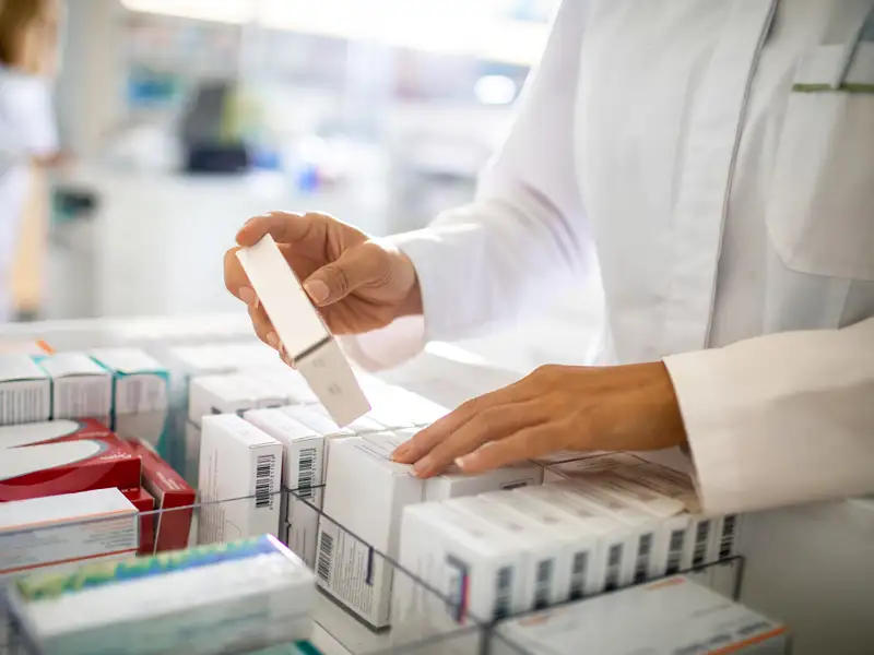 A pharmacist selects a medication from a case.