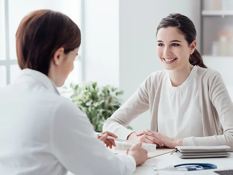 An agent speaks to a smiling woman at a white desk.