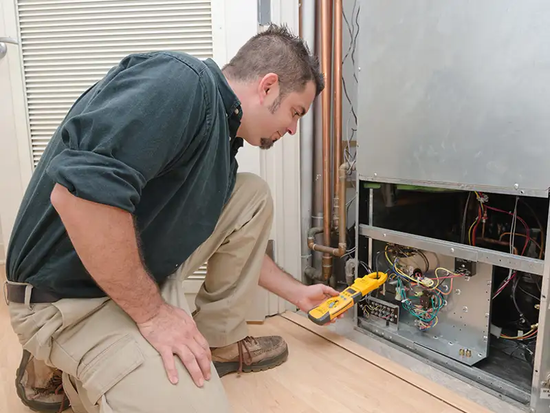 A technician inspects an electrical panel in a heating and ventilation unit.