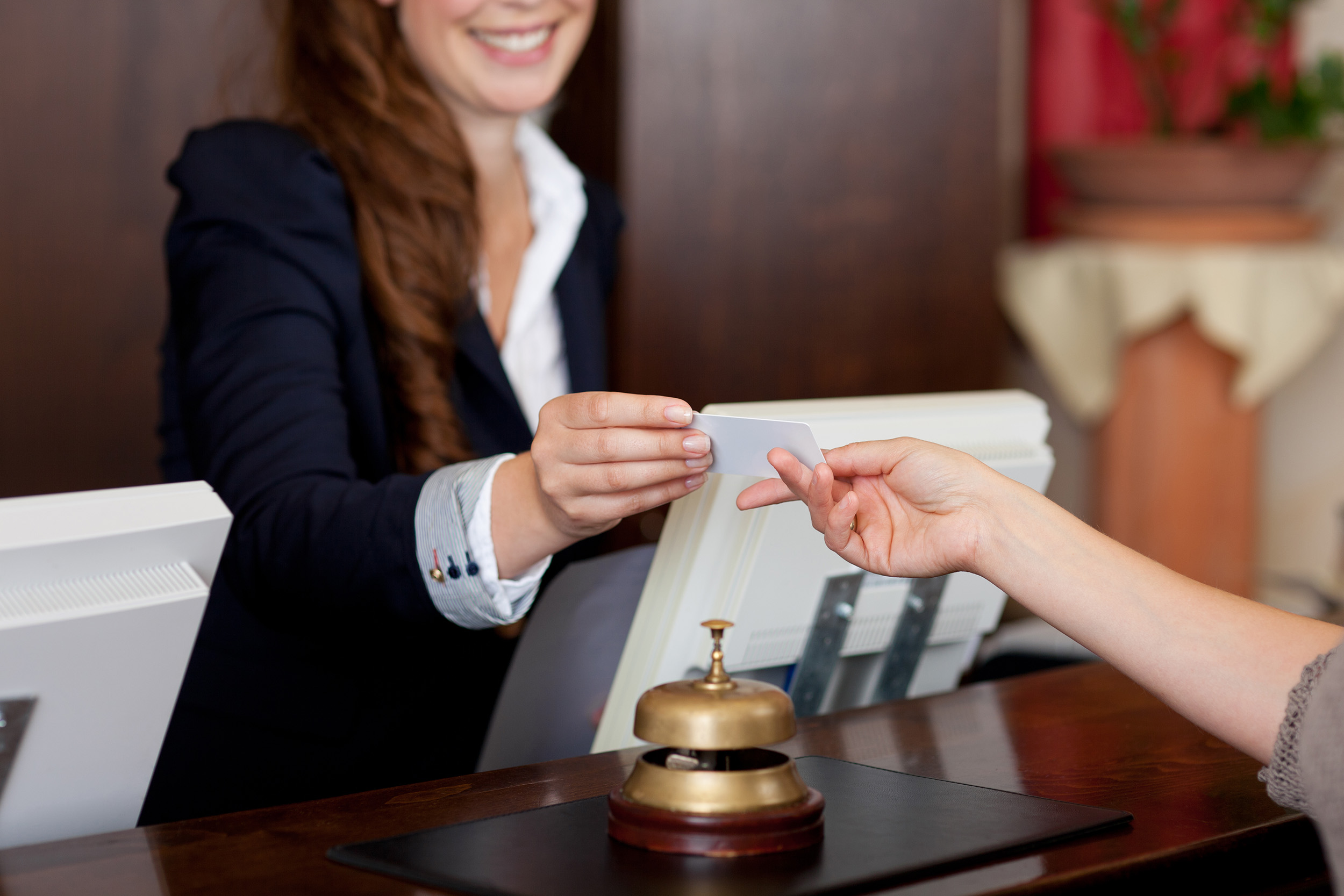  A clerk checks hands a hotel patron a key card.