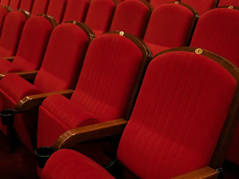 Plush red theatre seats await eager arts patrons.