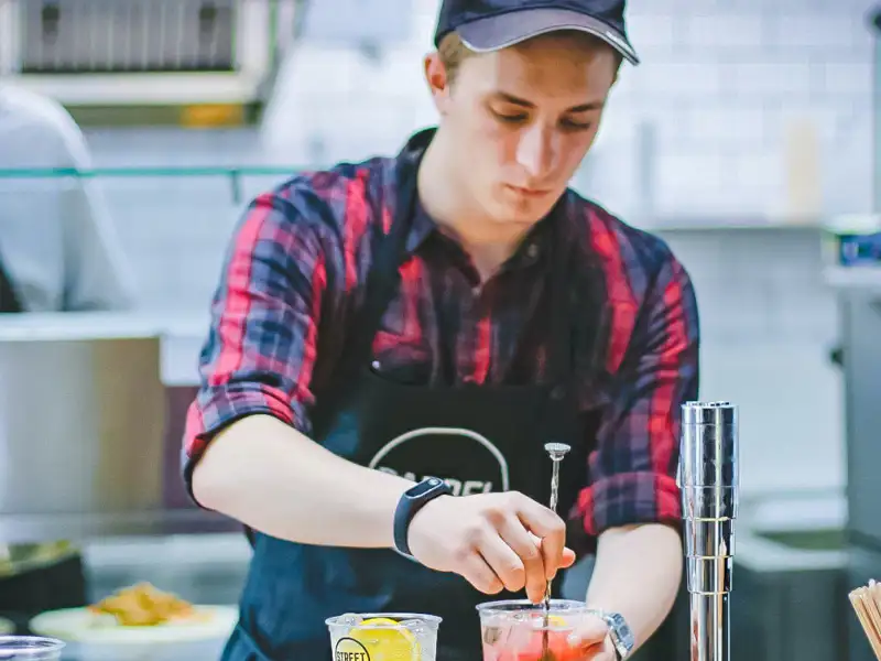 Bartender mixing a cocktail in the back kitchen.