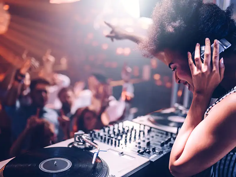 A club DJ reaches out to acknowledge the patrons on the dance floor.