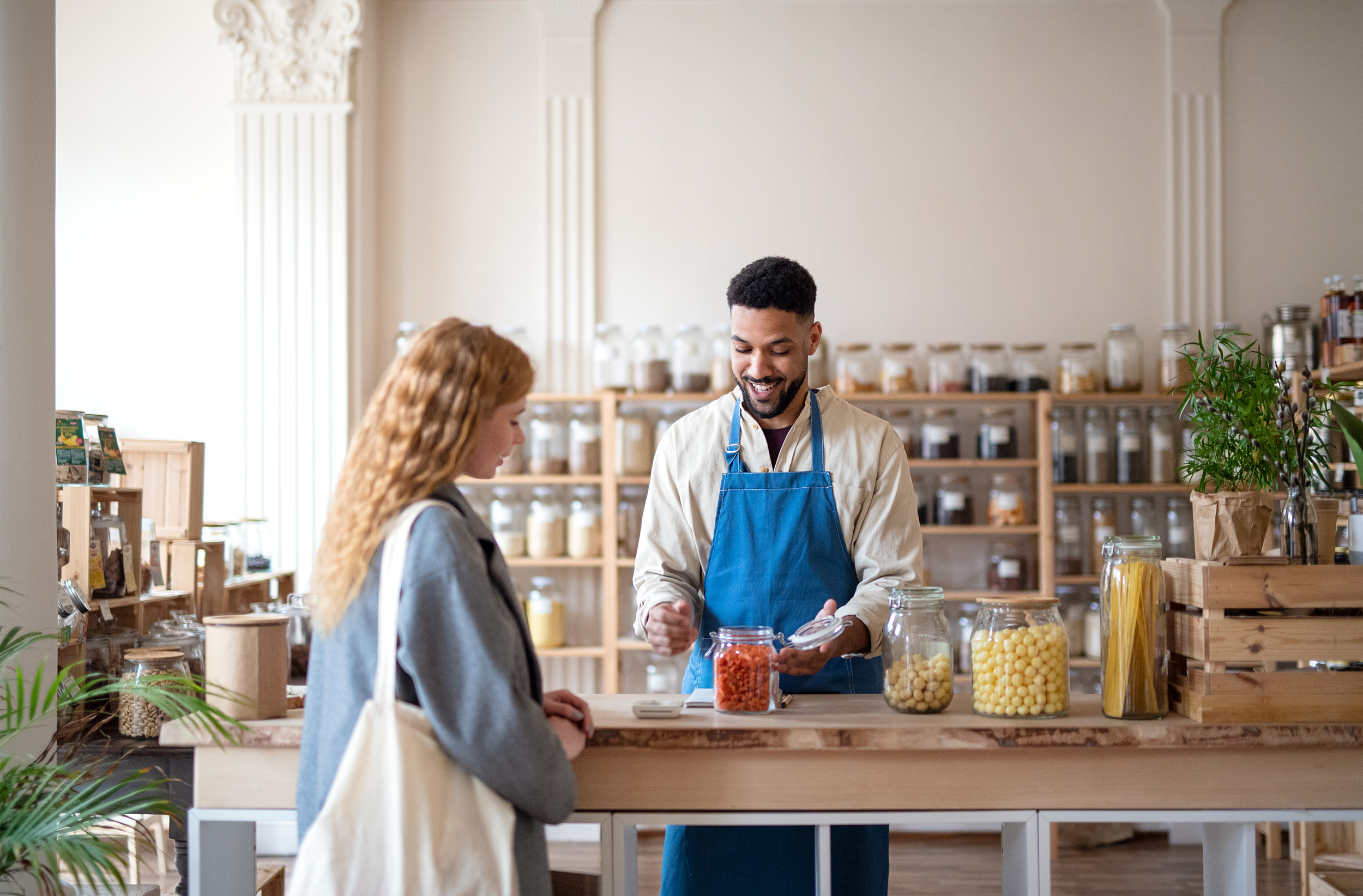 The smiling keeper of a small shop has a discussion with a patron.