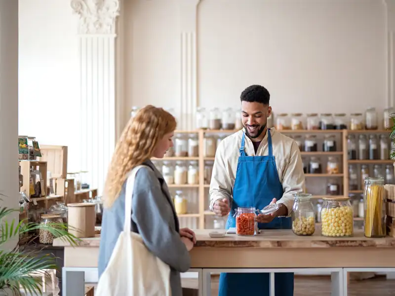 The smiling keeper of a small shop has a discussion with a patron.