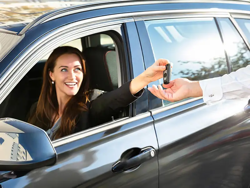 A woman retrieves the keys to her vehicle from a valet.