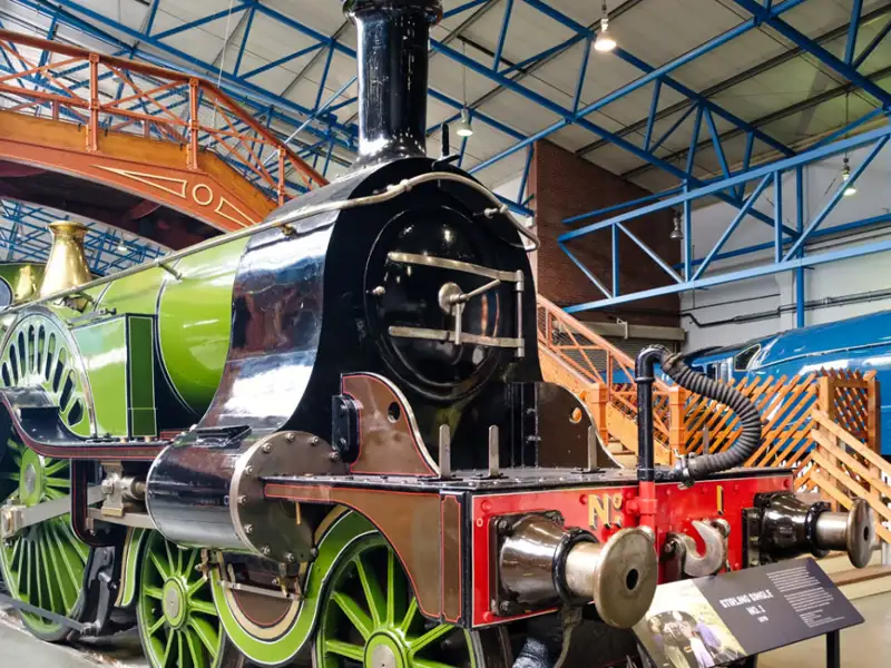 Close up of a green, black and red steam train in a museum.