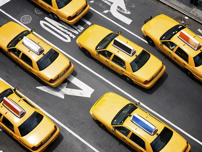 An overhead view of yellow taxicabs on a wide urban street.