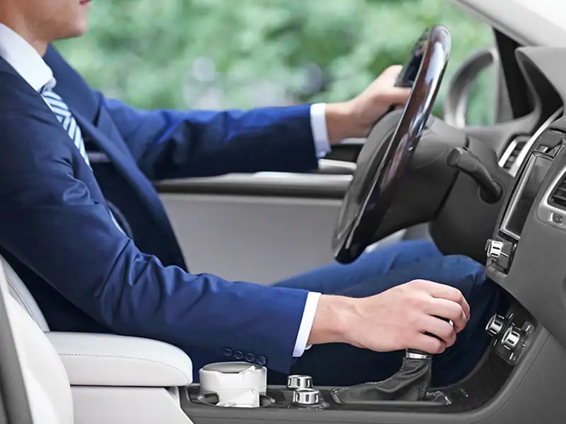 Interior view of a driver in a business suit shifting a passenger vehicle.