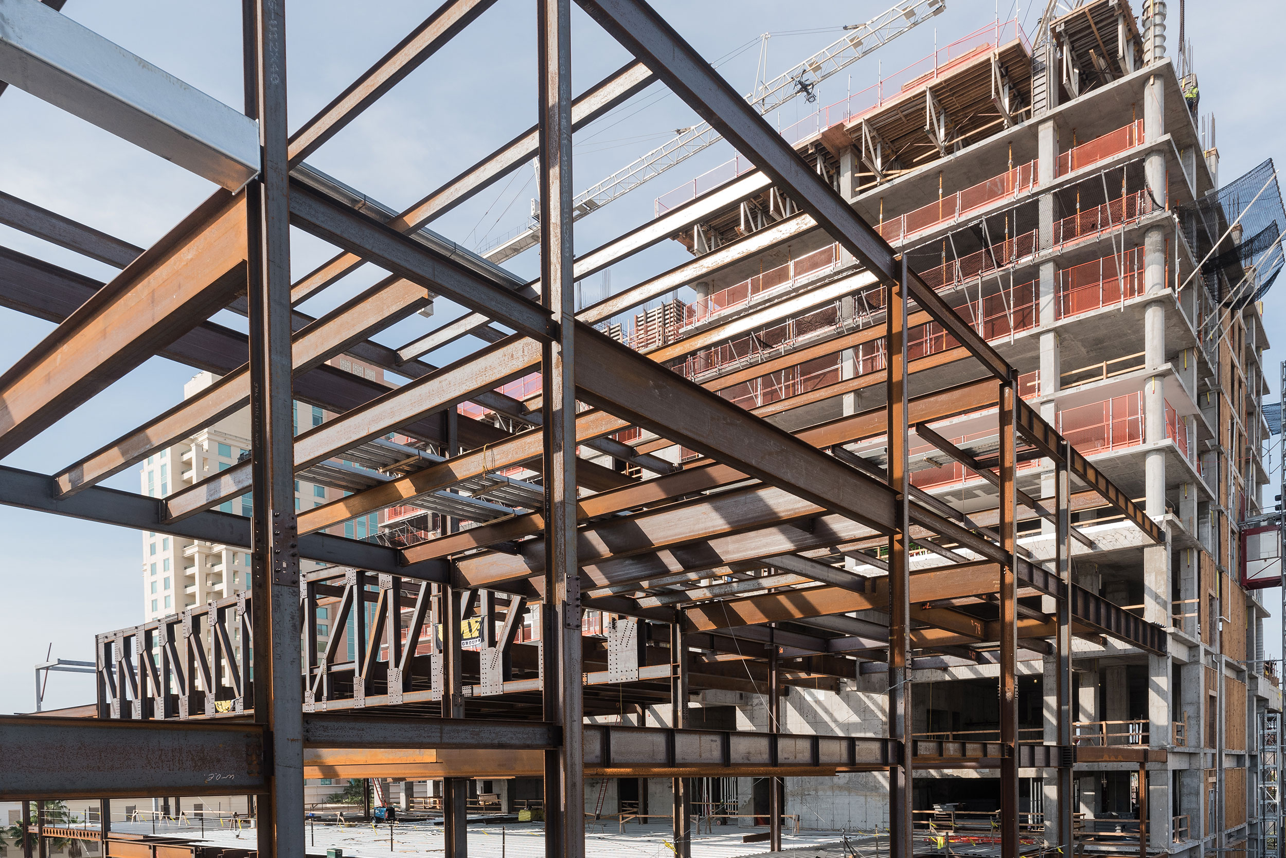 A grid of steel beams frame a large building under construction.