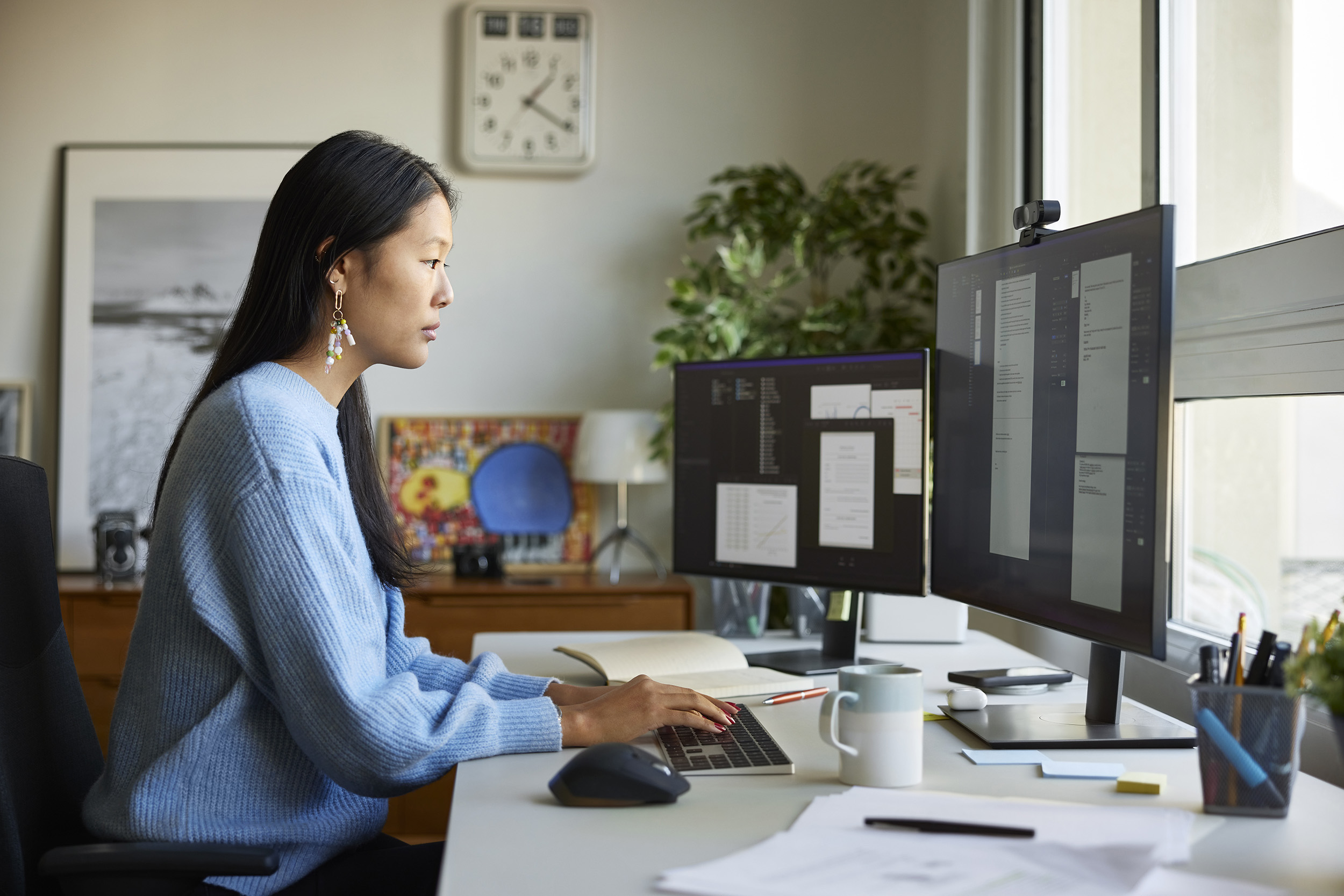 A woman focuses on a computer screen as she works in a home office.