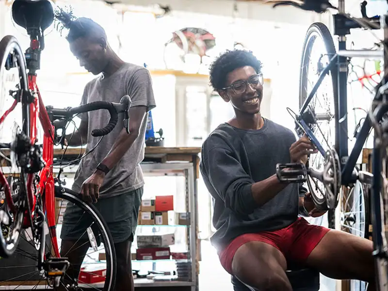 Two young technicians work on cycles in a pedal cycle repair shop.