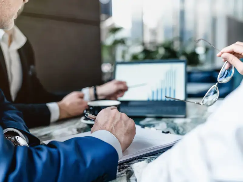 A group of business professionals study a chart on a laptop.