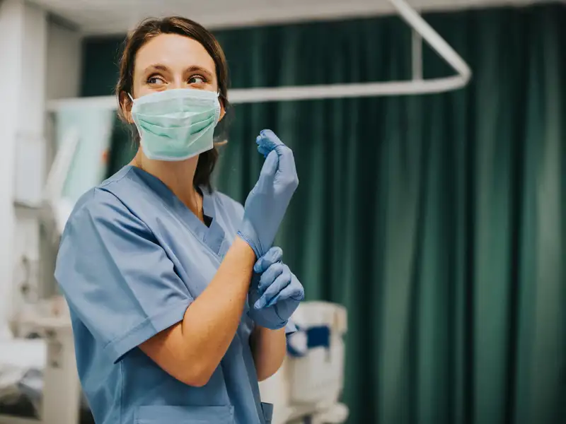 A medical professional donns gloves in preparation for surgery.