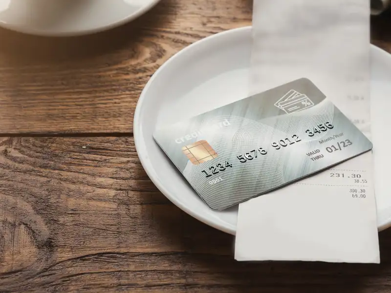A credit card sits on a restaurant table awaiting pickup by waitstaff.