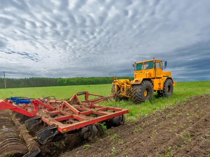 A tractor plowing a field on an overcast day.