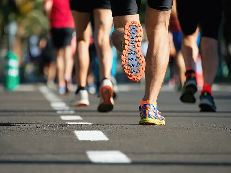 A low angle view of runners feet and legs on a street course.