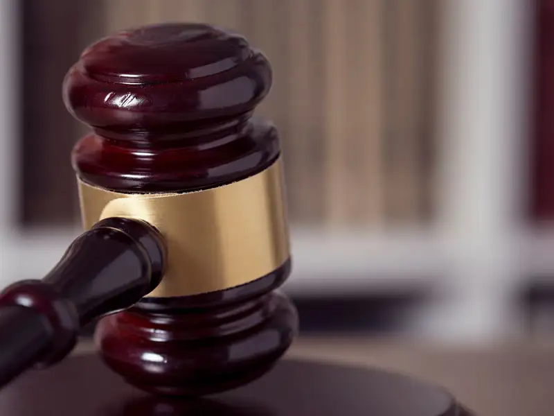 Close up of a judge gavel and law books in the background of a courtroom.