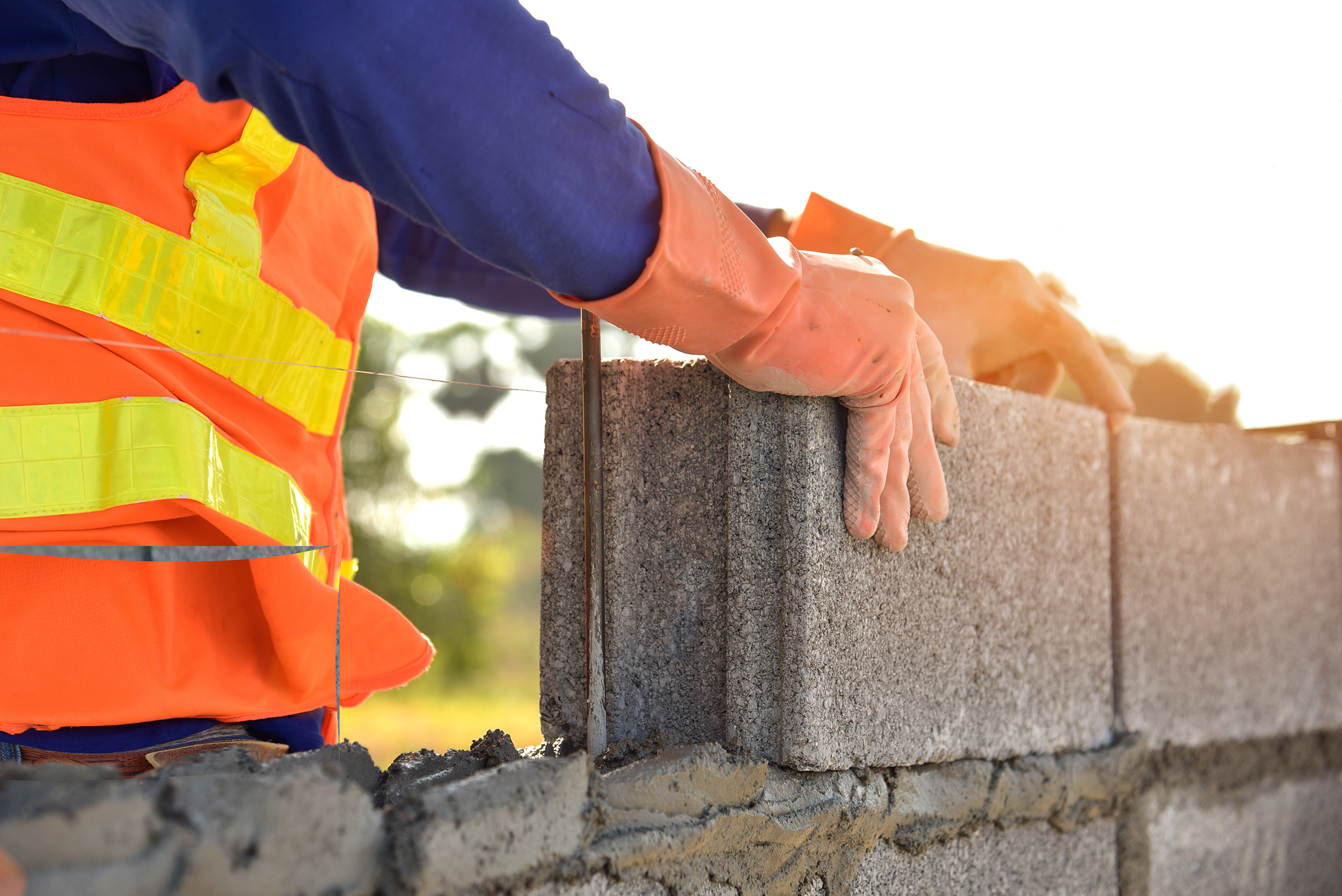 A worker lays cinder blocks.