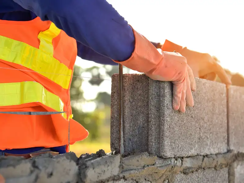 A worker lays cinder blocks.