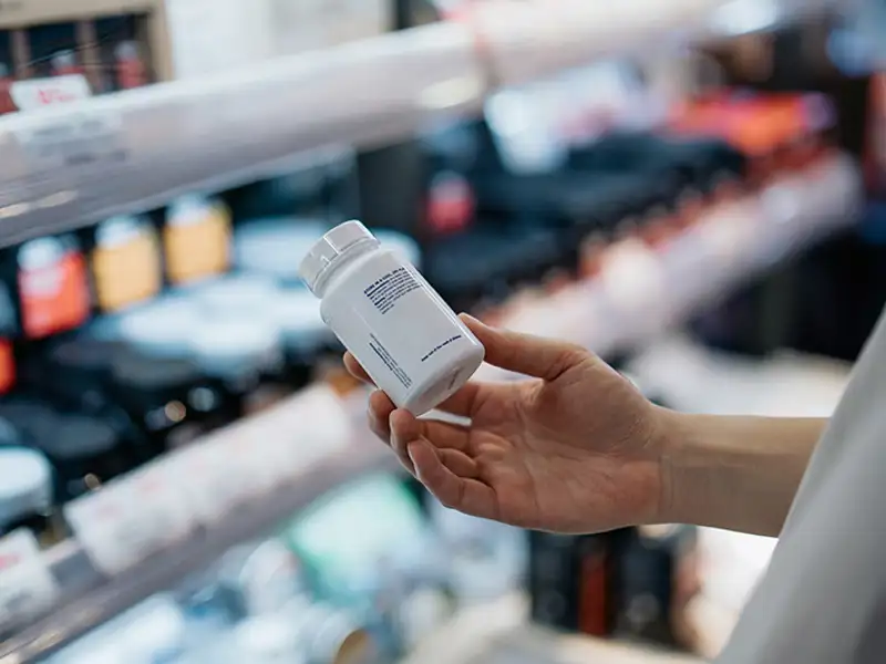 A shopper studies the fine print on the back of a medication bottle.