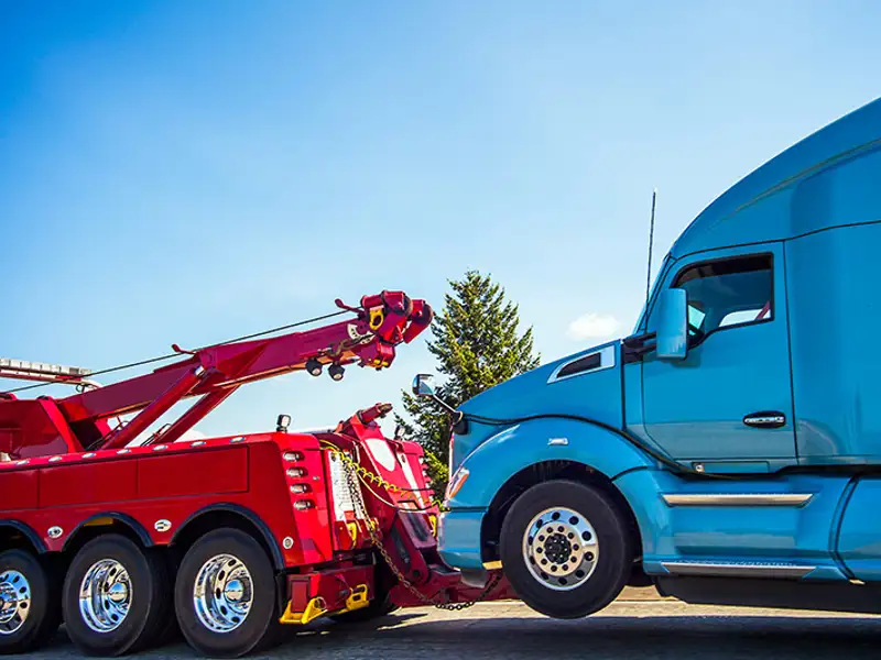 A large red tow truck lifts the cab of a disabled lorry.