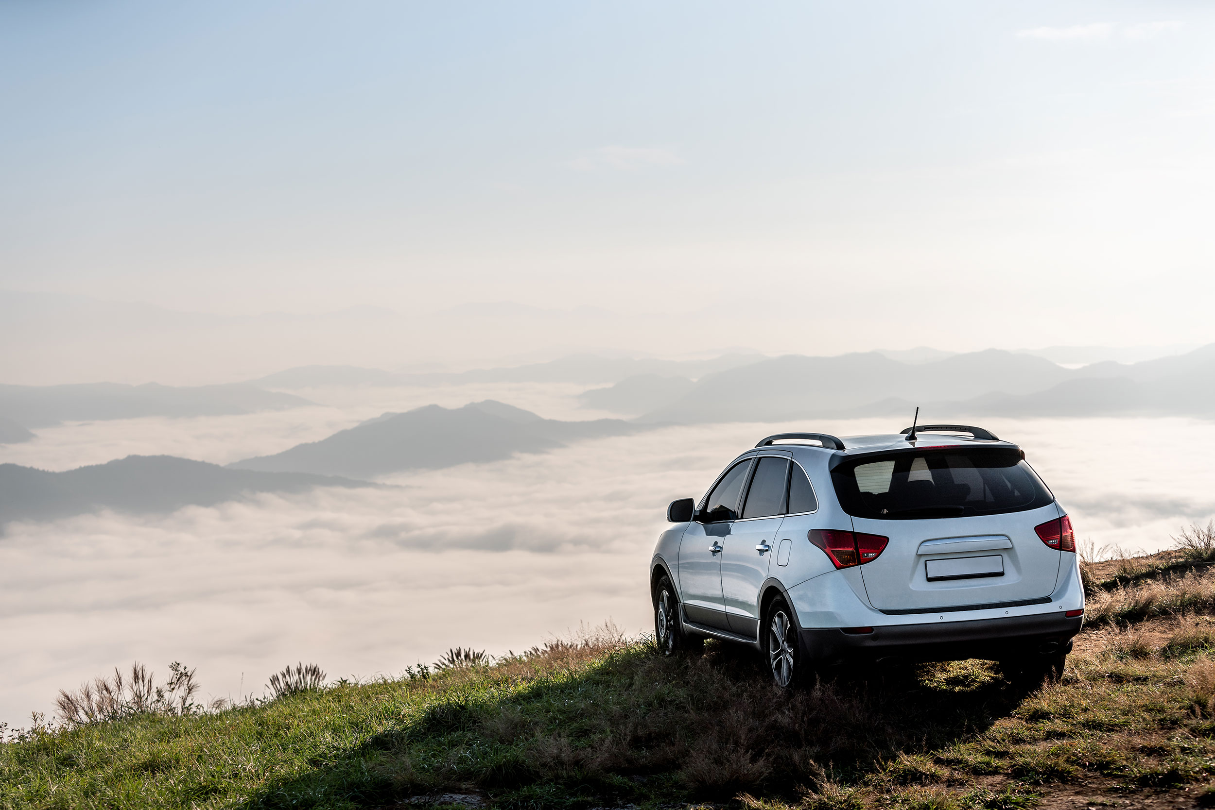 A sport utility vehicle parked on a hilltop, overlooking a cloud-filled valley.