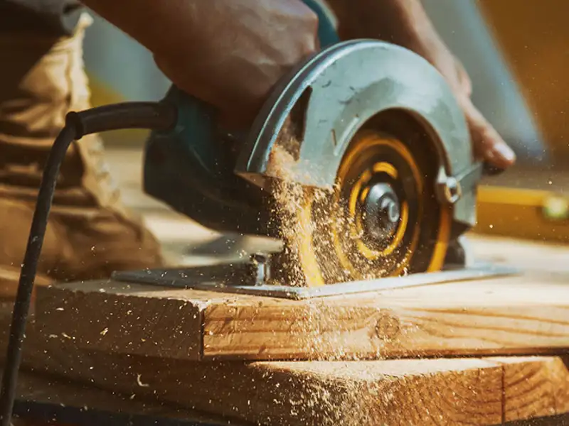 A skill saw cuts through a piece of wood.