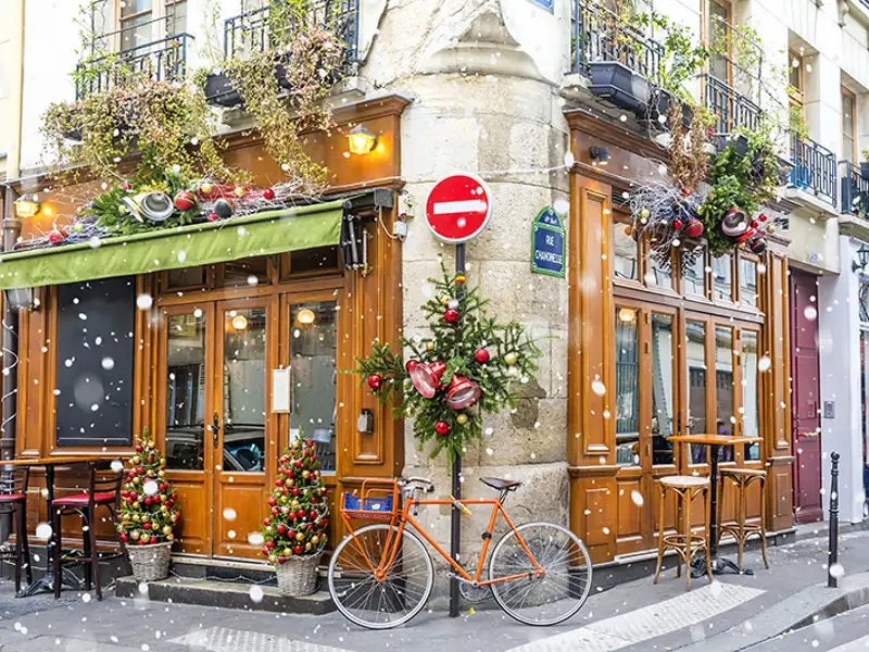 Snow falls in front of a bicycle retail shop during a winter holiday.